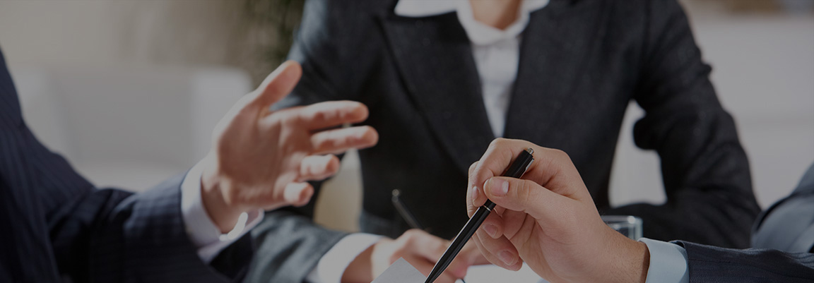 A team of three business consultants at a table, a hand with a pen makes notes